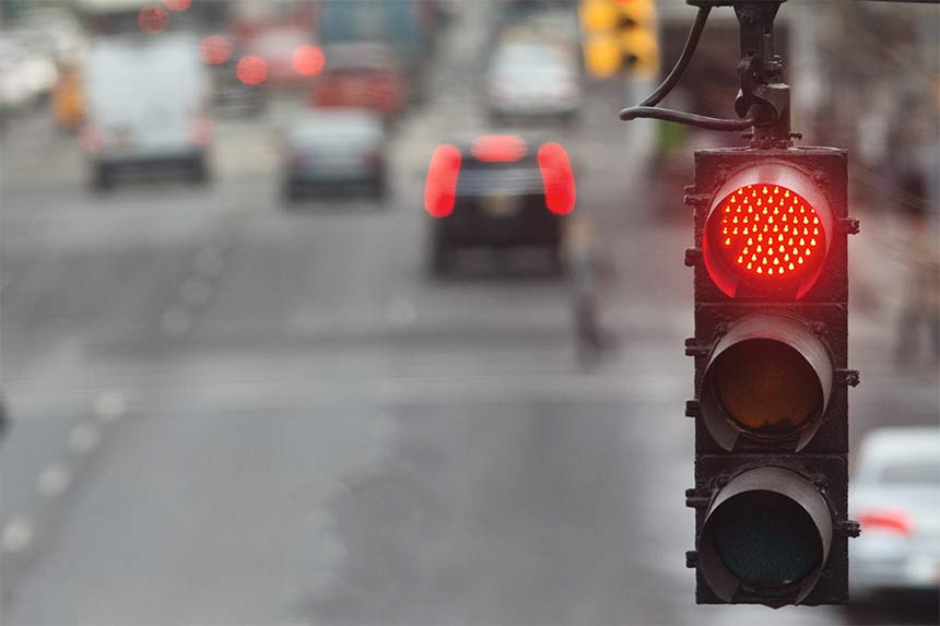Traffic light in the city with red signal on the background of the road